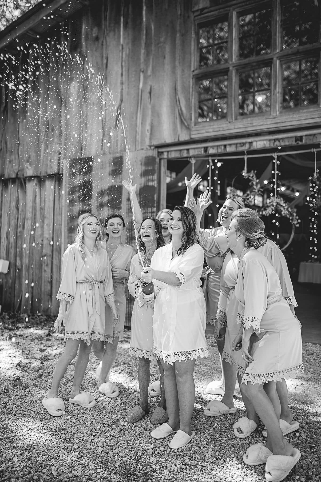 bride popping champagne bottle while bridesmaids cheer