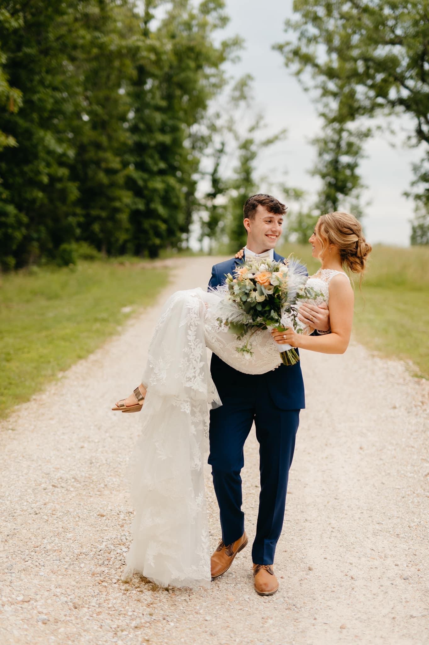 groom carrying bride down scenic gravel road