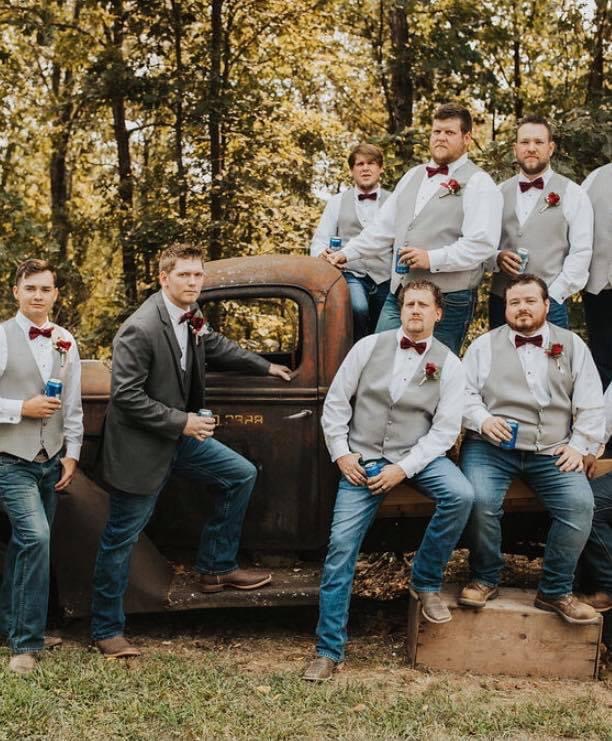 groom and groomsmen posing on antique truck